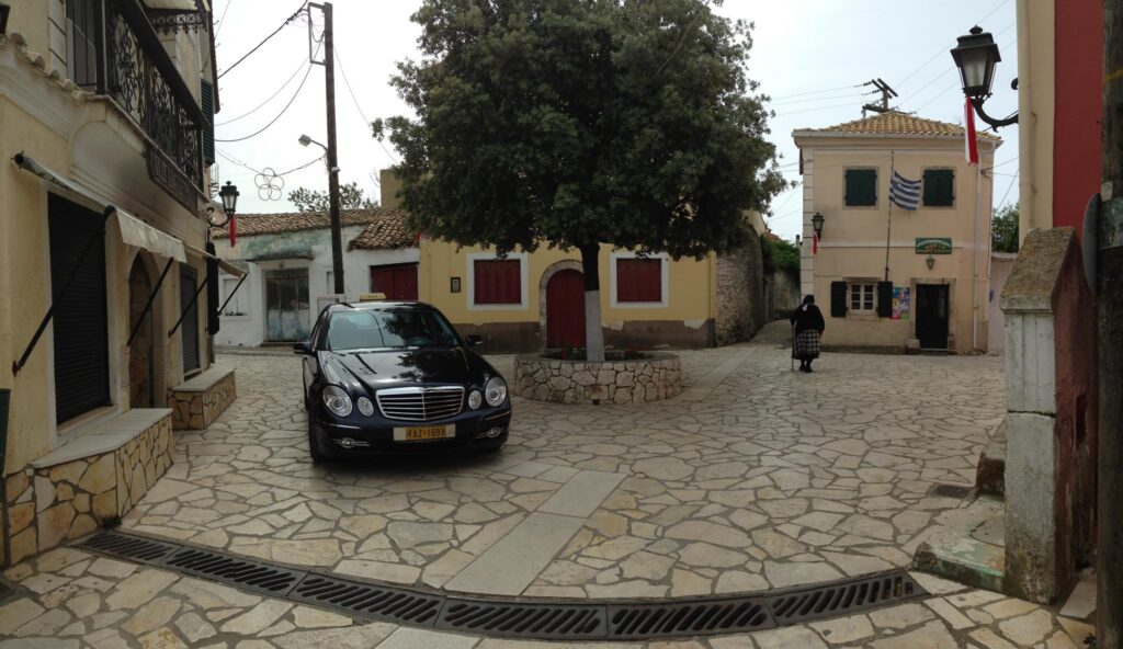 Corfu taxi parked in a village square during a private transfer and tour